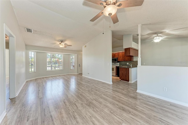 unfurnished living room featuring a textured ceiling, visible vents, baseboards, vaulted ceiling, and light wood-type flooring