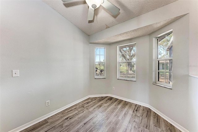 spare room featuring a textured ceiling, wood finished floors, a ceiling fan, and baseboards