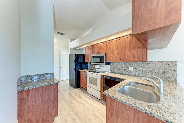 kitchen featuring light stone counters, light wood finished floors, visible vents, a sink, and black appliances