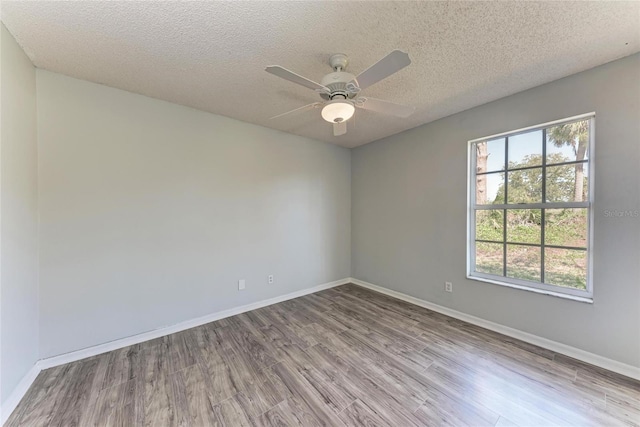 unfurnished room featuring a healthy amount of sunlight, a textured ceiling, baseboards, and wood finished floors