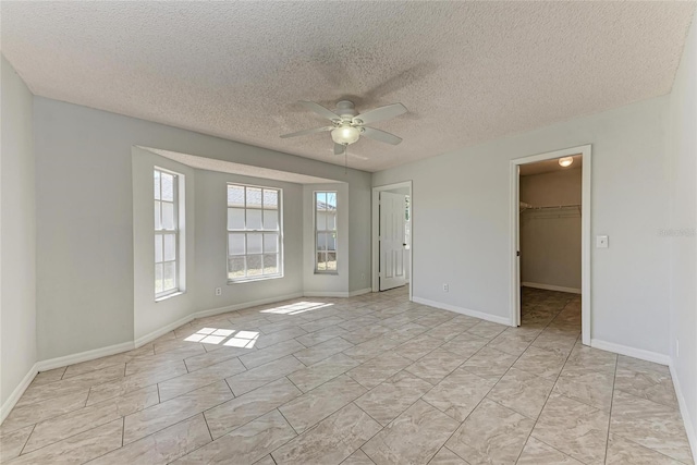 unfurnished room with ceiling fan, a textured ceiling, and baseboards