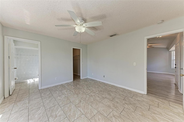 spare room with a textured ceiling, baseboards, visible vents, and a ceiling fan