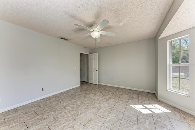 empty room with a ceiling fan, visible vents, a textured ceiling, and baseboards