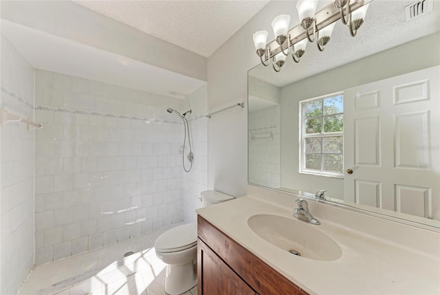 bathroom with visible vents, tiled shower, toilet, a textured ceiling, and vanity