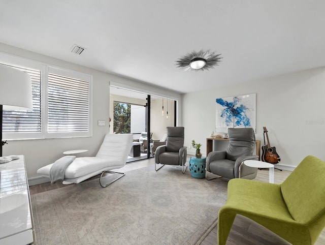 living area with wood finished floors, visible vents, and baseboards