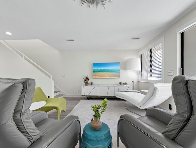 living room with stairway, wood finished floors, visible vents, and baseboards