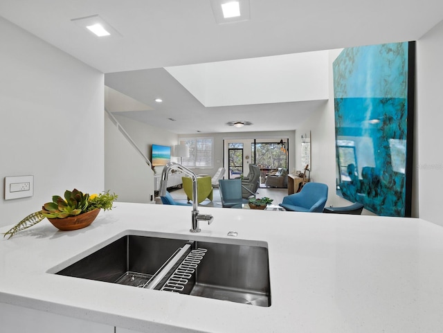 kitchen featuring open floor plan, light countertops, and a sink