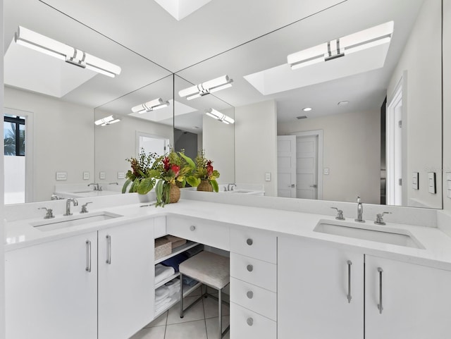 full bath with tile patterned floors, double vanity, a skylight, and a sink