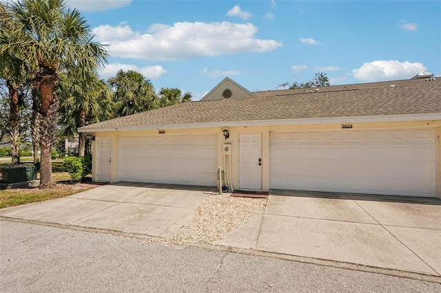 ranch-style house featuring driveway, a shingled roof, and stucco siding