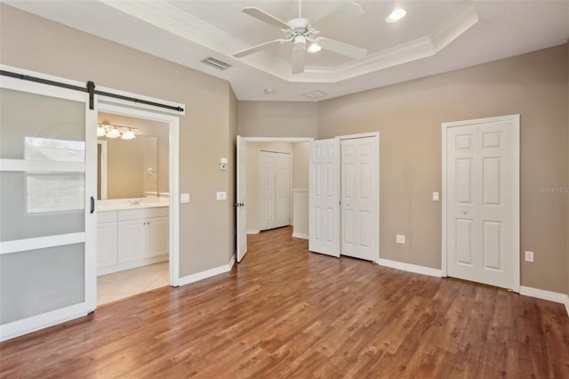 unfurnished bedroom with wood finished floors, a raised ceiling, visible vents, and crown molding