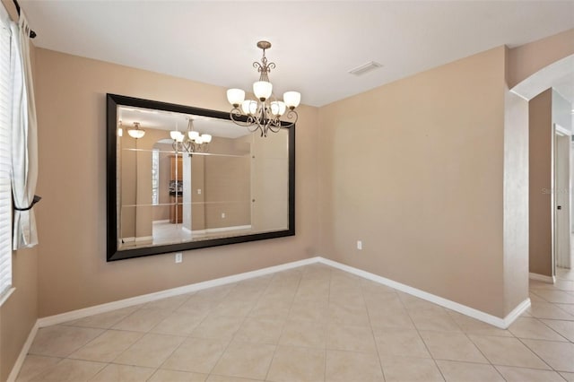 tiled empty room with a chandelier, visible vents, and baseboards