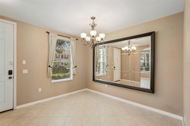 unfurnished dining area with baseboards, tile patterned flooring, and an inviting chandelier