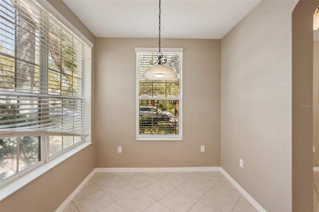 unfurnished dining area with light tile patterned flooring and baseboards