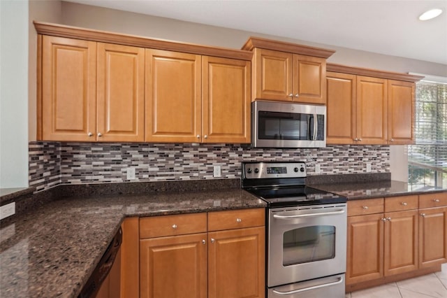 kitchen featuring appliances with stainless steel finishes, dark stone counters, light tile patterned floors, and tasteful backsplash