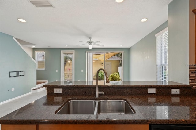 kitchen featuring a wealth of natural light, dark stone countertops, and a sink