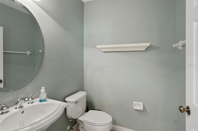 bathroom featuring baseboards, a sink, and toilet