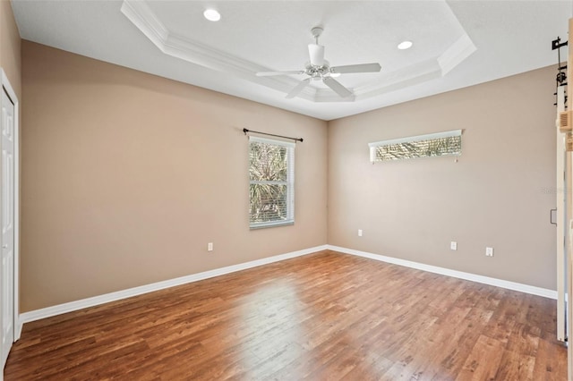 unfurnished bedroom featuring baseboards, a raised ceiling, and wood finished floors