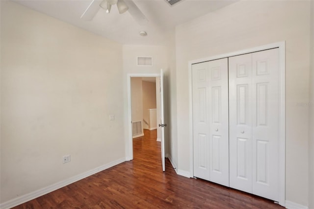 unfurnished bedroom with dark wood-type flooring, a closet, visible vents, and baseboards