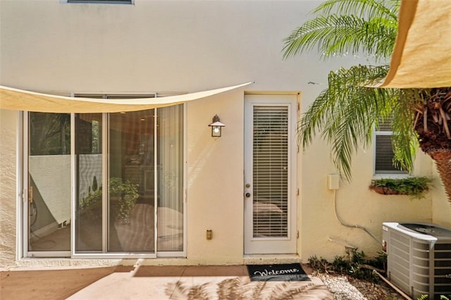 entrance to property with cooling unit and stucco siding