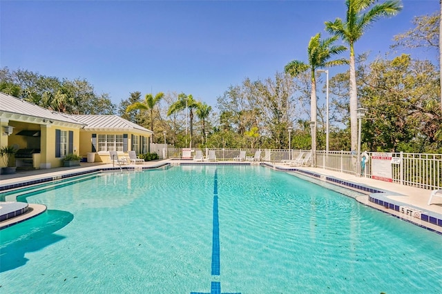 community pool with a patio area and fence