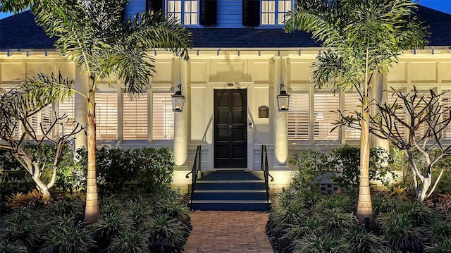 view of exterior entry featuring roof with shingles