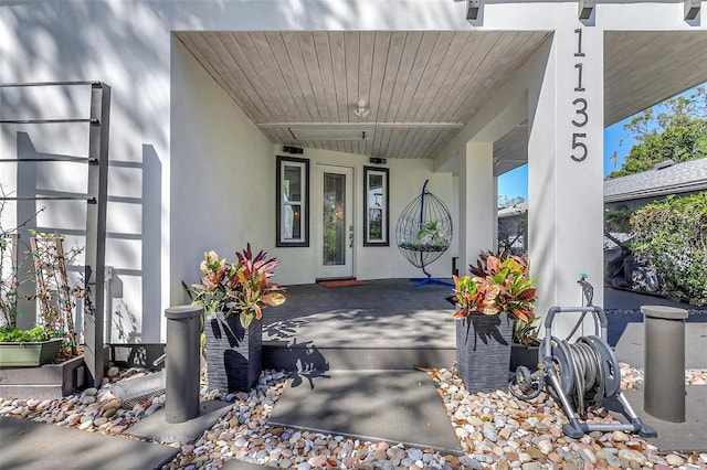 doorway to property featuring covered porch and stucco siding