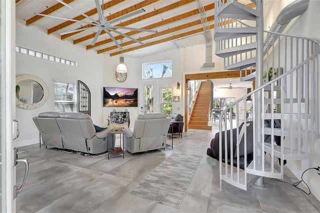 living room with beam ceiling, baseboards, a high ceiling, concrete flooring, and stairs