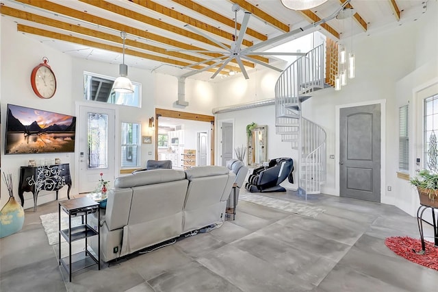living area with stairs, concrete flooring, baseboards, a high ceiling, and beam ceiling