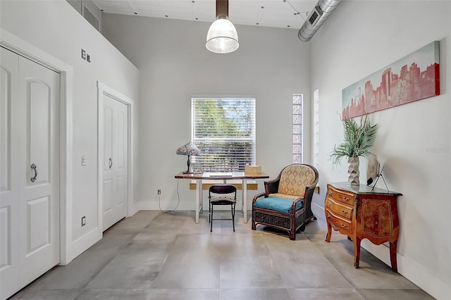 sitting room featuring a towering ceiling and baseboards