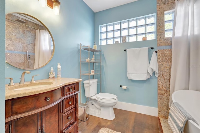 full bath featuring wood finished floors, vanity, baseboards, a tile shower, and toilet