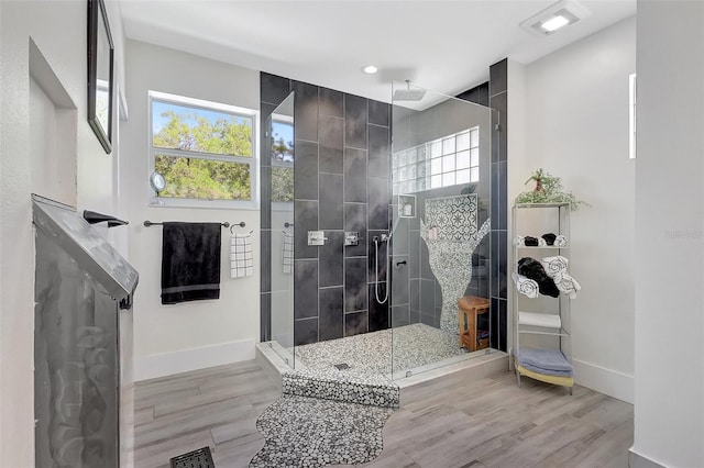 full bath with baseboards, wood finished floors, visible vents, and tiled shower