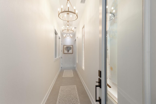 hall with a chandelier, visible vents, and baseboards