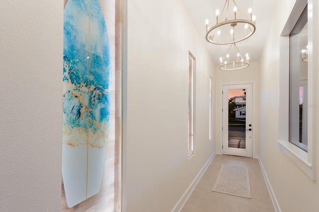 hallway with baseboards and a chandelier