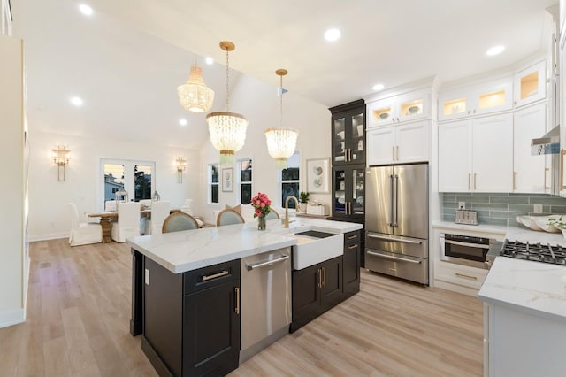 kitchen featuring a sink, light wood-type flooring, appliances with stainless steel finishes, white cabinetry, and a kitchen island with sink