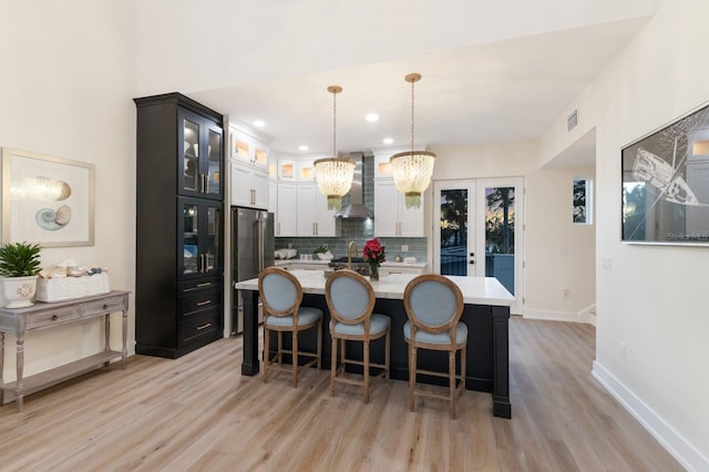 kitchen with light countertops, wall chimney range hood, visible vents, and high end refrigerator