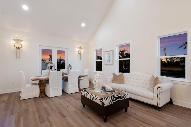 living area featuring recessed lighting, baseboards, high vaulted ceiling, and light wood-style flooring