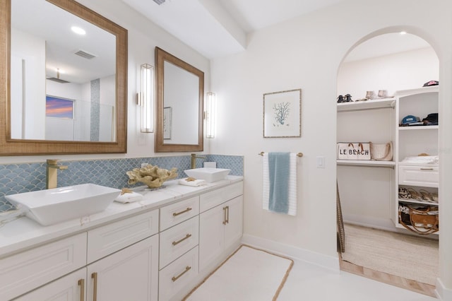 full bathroom featuring visible vents, tasteful backsplash, a walk in shower, and a sink