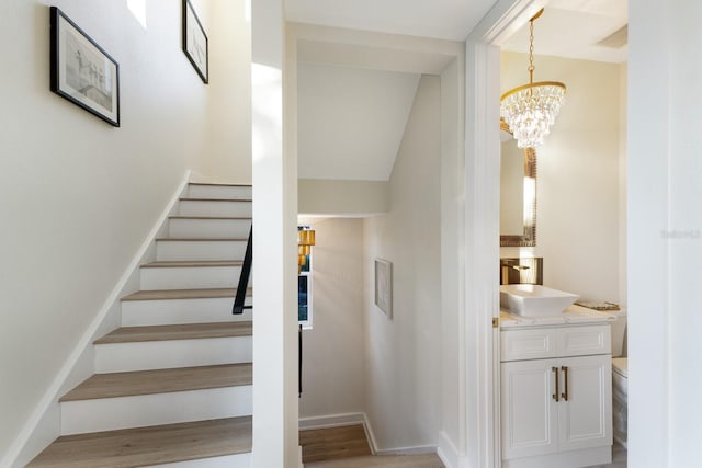 stairs featuring baseboards and a notable chandelier