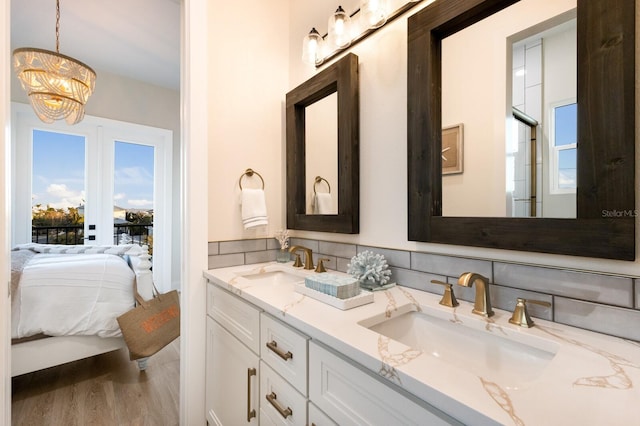 bathroom with double vanity, connected bathroom, wood finished floors, and a sink