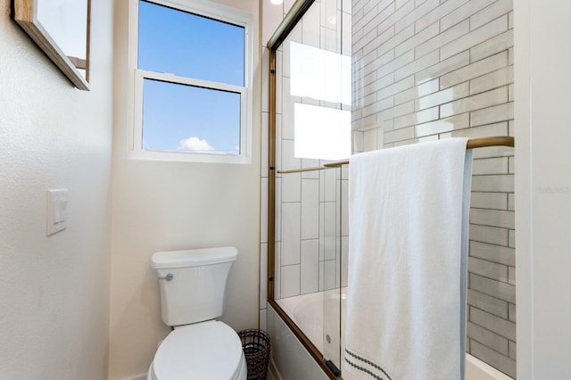 bathroom with toilet and bath / shower combo with glass door