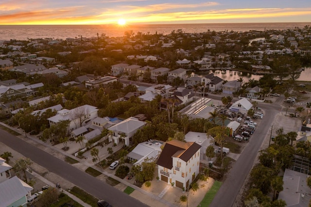 aerial view at dusk featuring a water view and a residential view