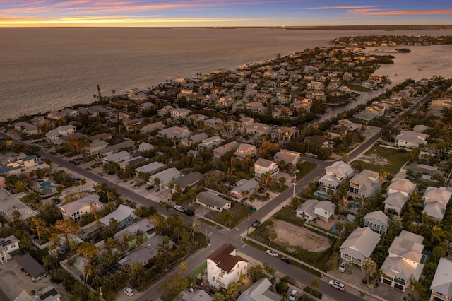 aerial view at dusk with a residential view and a water view