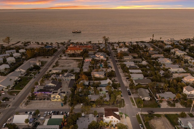 aerial view at dusk featuring a residential view and a water view