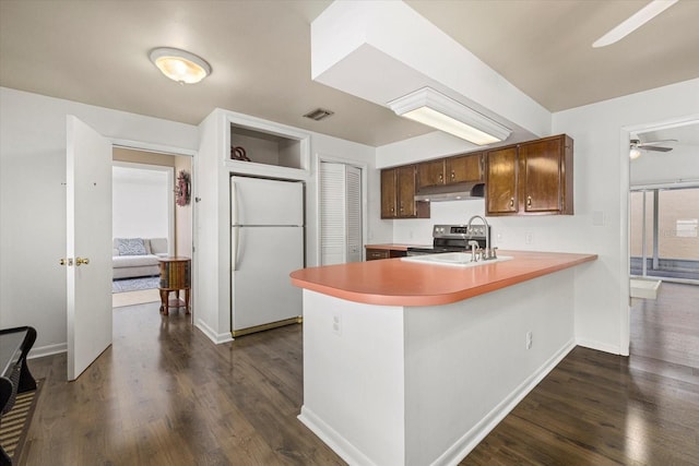 kitchen with visible vents, freestanding refrigerator, a peninsula, under cabinet range hood, and a sink