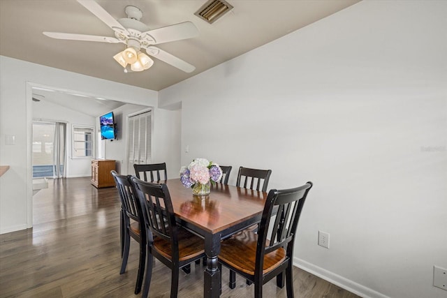 dining area with dark wood-style flooring, a ceiling fan, visible vents, vaulted ceiling, and baseboards