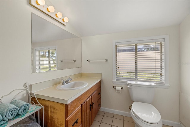 half bathroom with tile patterned flooring, toilet, vanity, baseboards, and vaulted ceiling