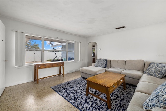 living room with arched walkways, speckled floor, visible vents, and baseboards