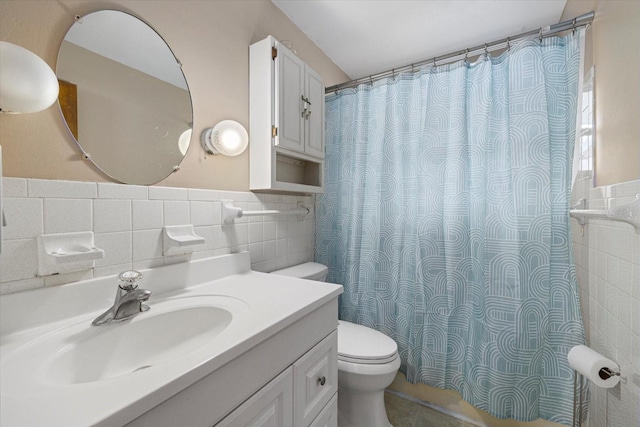 bathroom featuring curtained shower, toilet, vanity, tile walls, and wainscoting