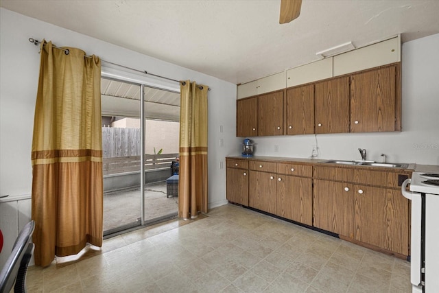 kitchen with ceiling fan, electric range, a sink, and brown cabinets