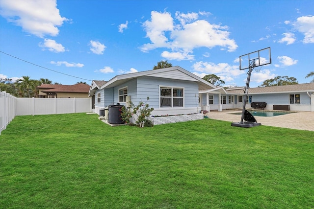 rear view of house featuring a patio, a lawn, a fenced backyard, and a fenced in pool